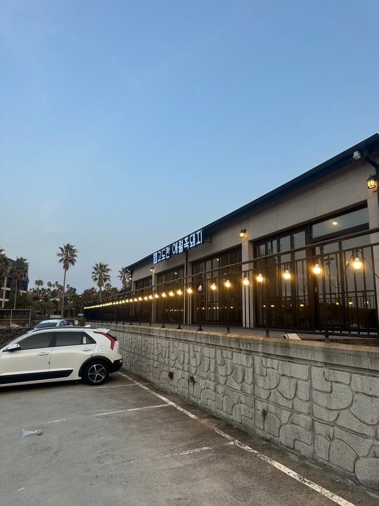 Exterior of Godokan Aewol Black Pork at dusk, with string lights along the terrace