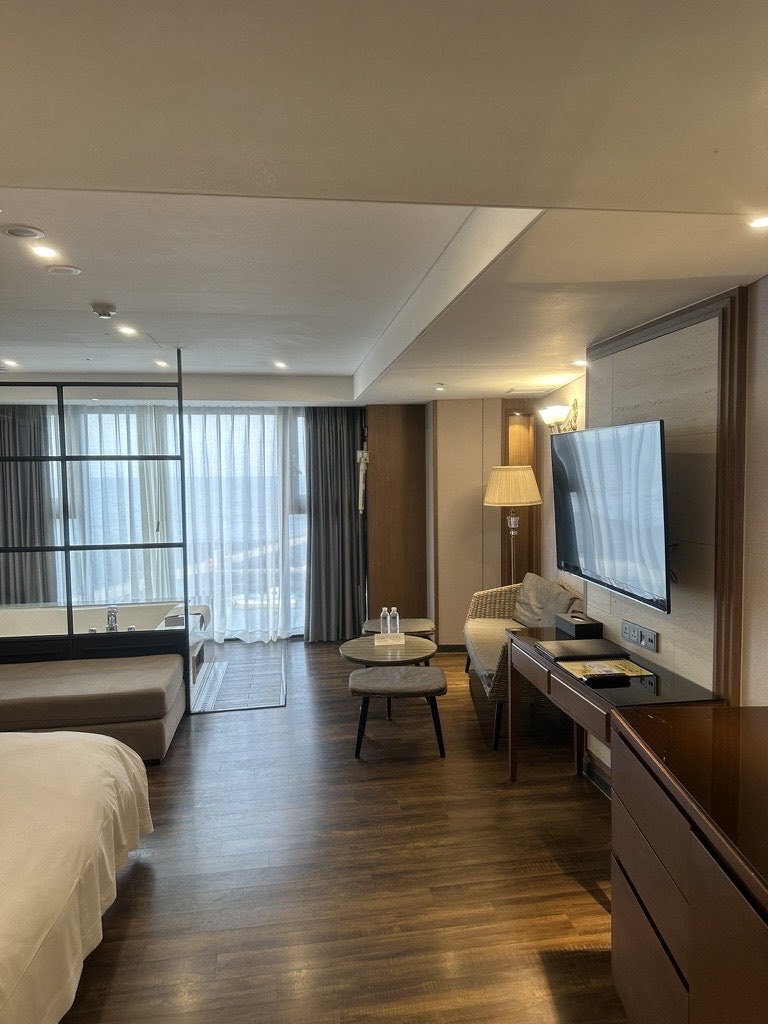 Inside the Suite Ocean room at Dyne Oceano Hotel: bed, seating area and the glass-walled jacuzzi corner