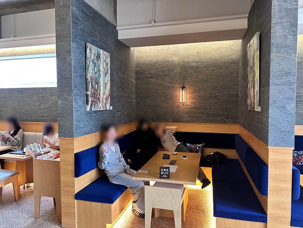 Semi-enclosed group booth at Joogiyul with navy sofas, gray stone walls and artwork, with a group seating sign on the table
