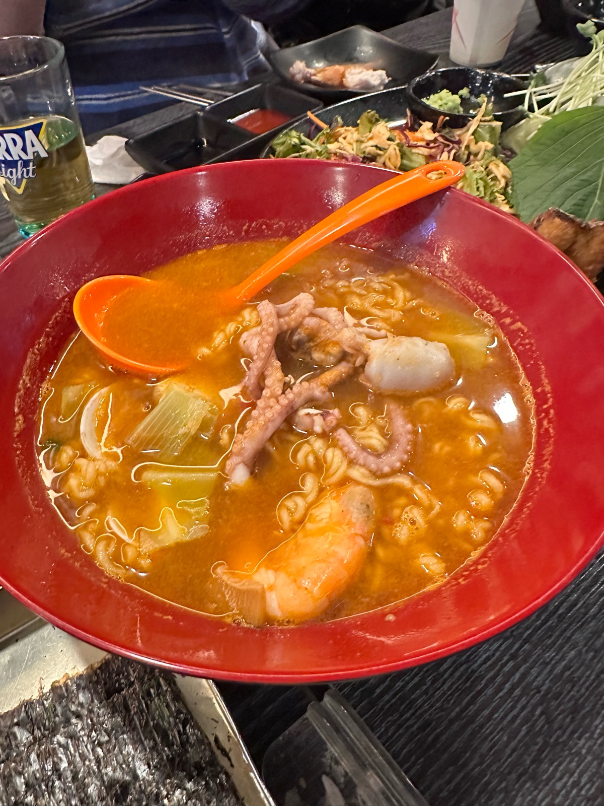 Squid ramyeon in a red bowl topped with squid legs and shrimp